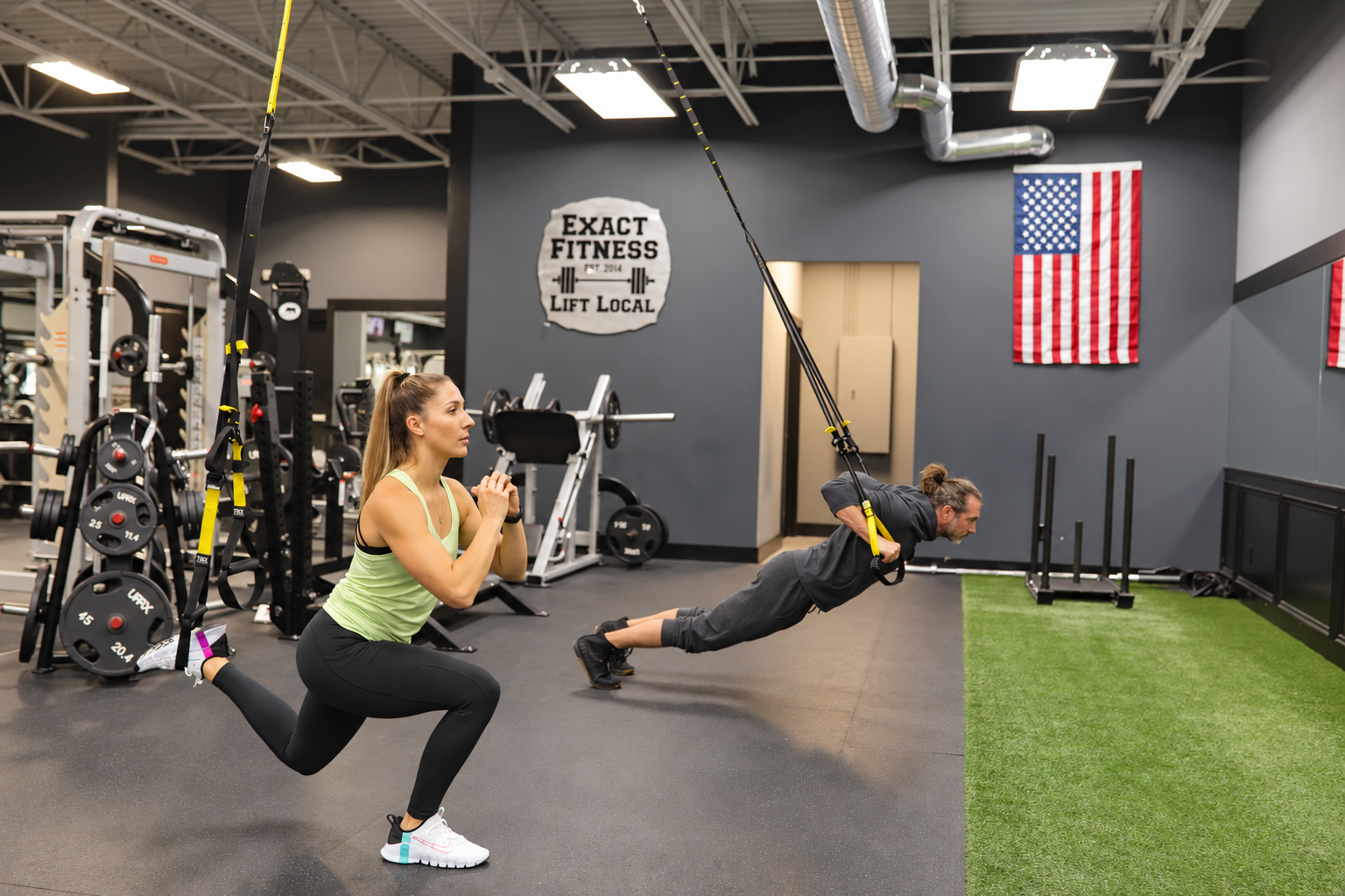 Two people training at Exact Fitness, using a split squat and suspension straps